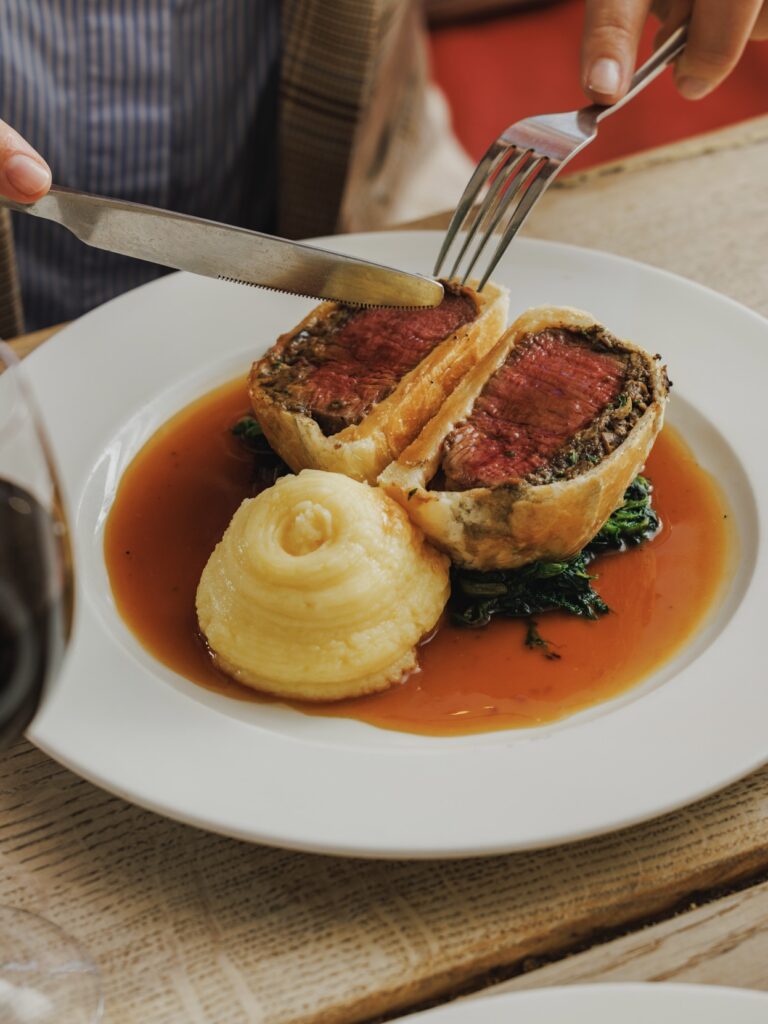 Beef Wellington wrapped in golden flaky pasty, with buttery mash and gravy.
